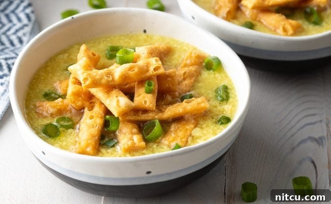 Cozy Kitchen Egg Drop Soup 7 A bowl of egg drop soup topped with crispy noodles and slice green onions.