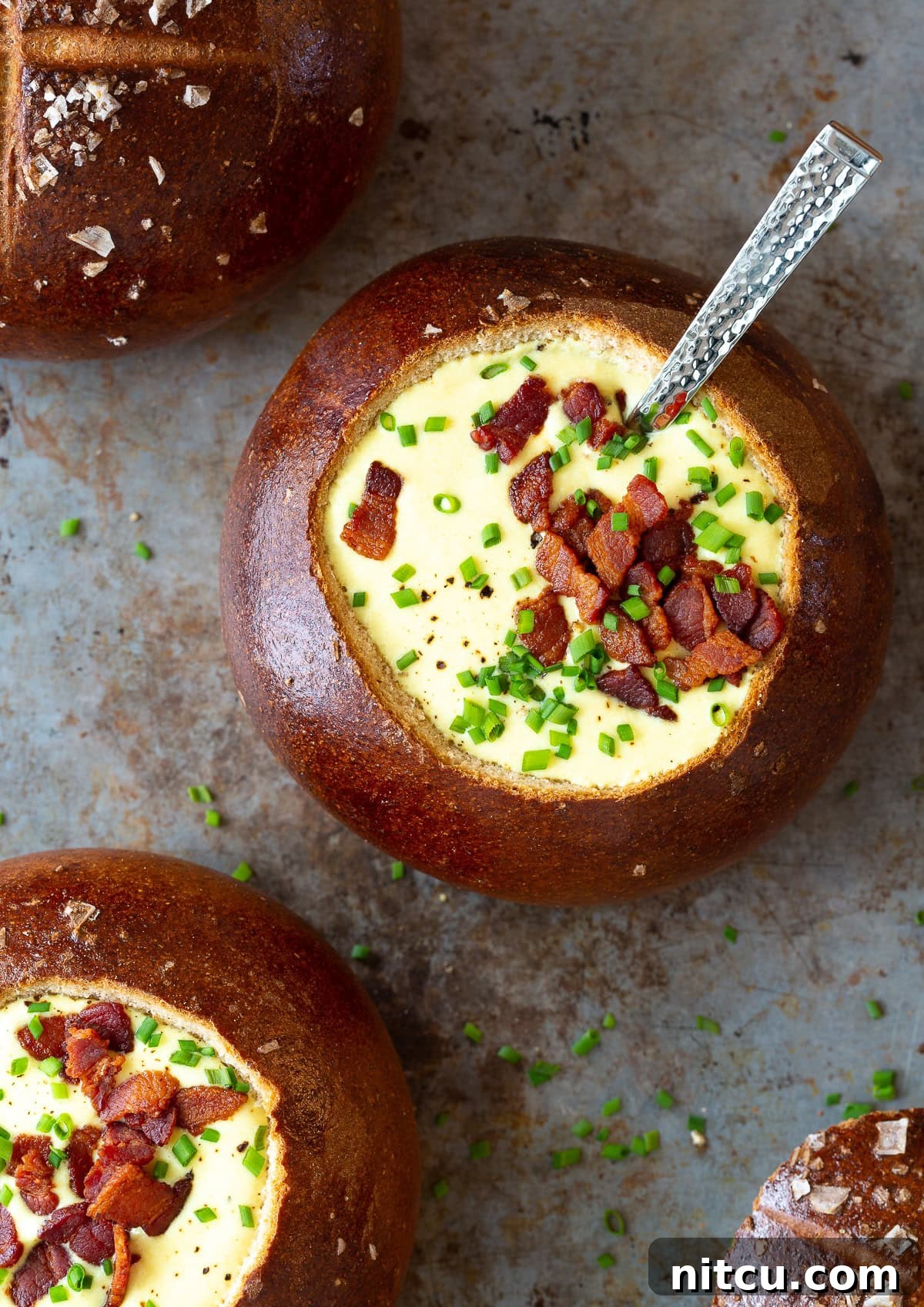 Overhead shot of creamy Irish Beer Cheese Soup served in a bread bowl with crumbled bacon topping.