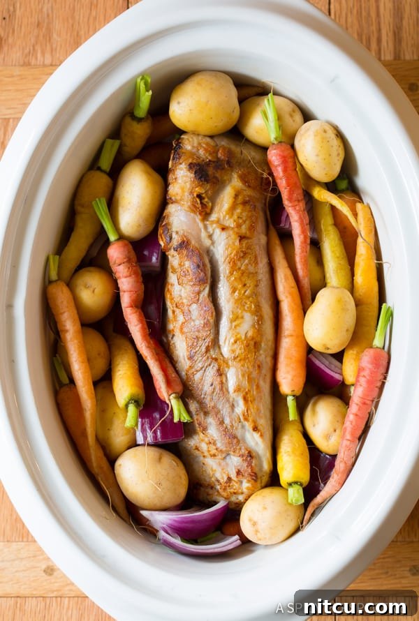Melt-in-Your-Mouth Slow Cooker Pork Loin and Root Veggies 5 Pork tenderloin and carrots placed in a crockpot before slow cooking