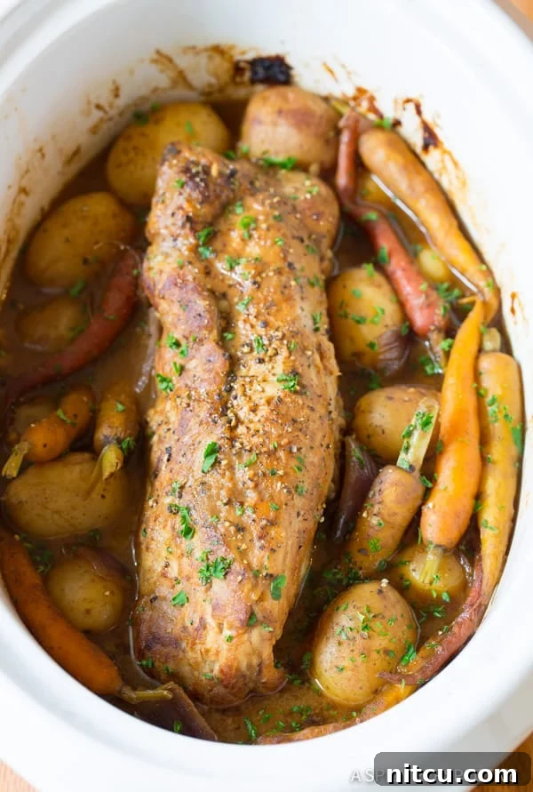 Melt-in-Your-Mouth Slow Cooker Pork Loin and Root Veggies 9 Crock Pot Pork Loin with Vegetables, freshly slow-cooked and garnished with parsley