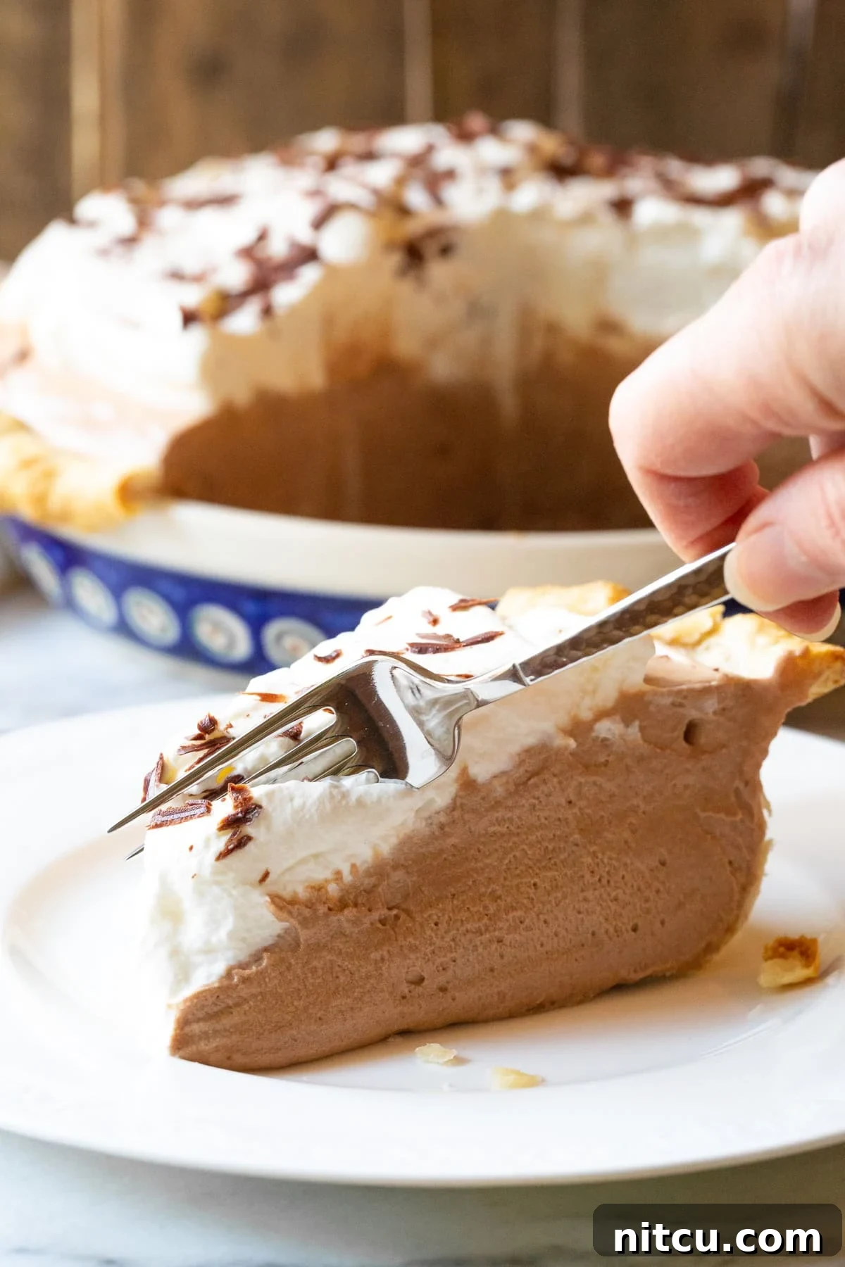 Chocolate Pie Recipe #ASpicyPerspective #FrenchSilkPie #SilkPie #FrenchSilkPieRecipe #ChocolateSilkPie #Chocolate #Silky #Fluffy #Pie #Dessert The best French Silk Pie, with a fork poised to cut the very first bite, highlighting its enticing layers.