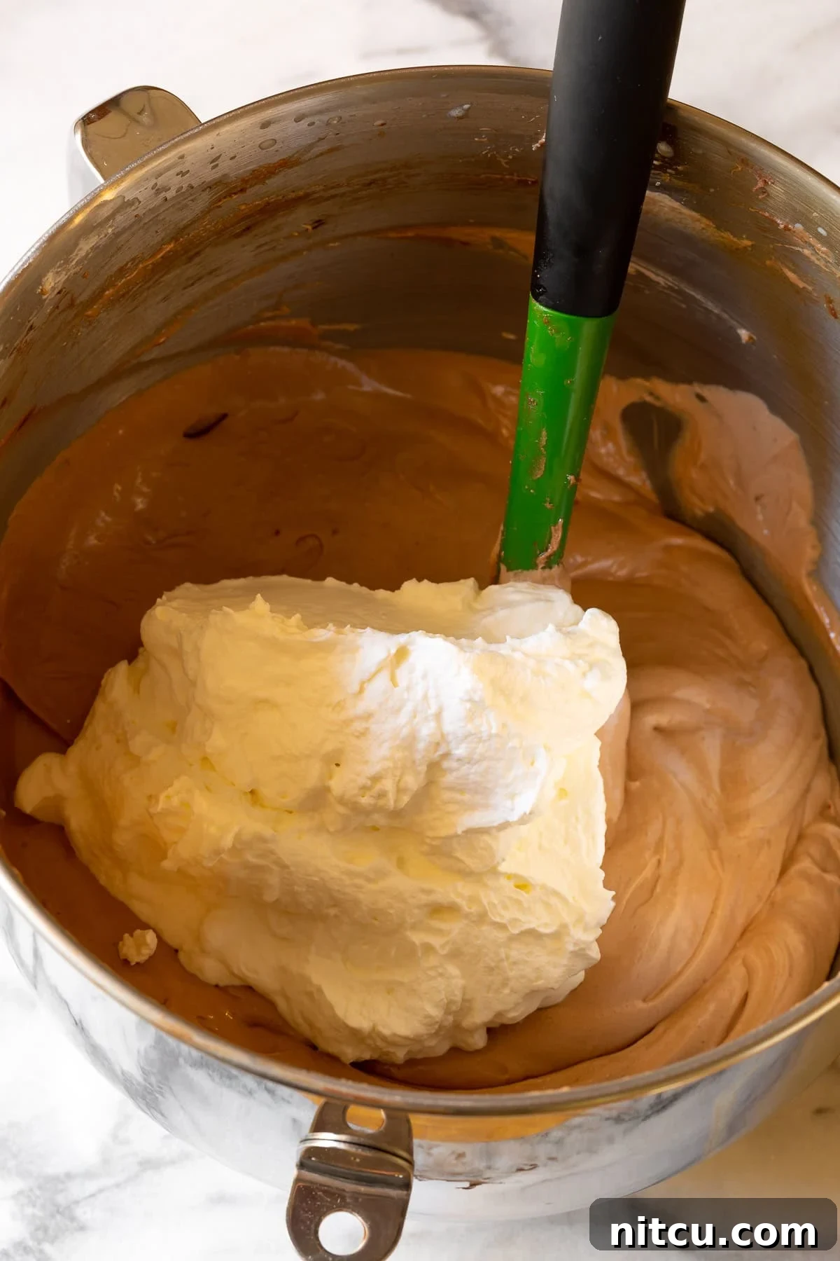Velvety French Silk Pie 4 Whipped cream being gently folded into the rich chocolate filling mixture with a spatula.
