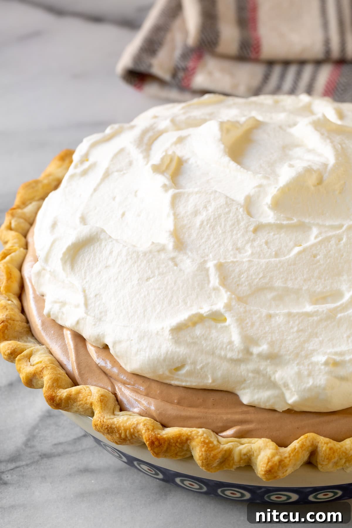 Velvety French Silk Pie 5 A completed pie crust filled with chocolate filling and topped with a generous layer of whipped cream.