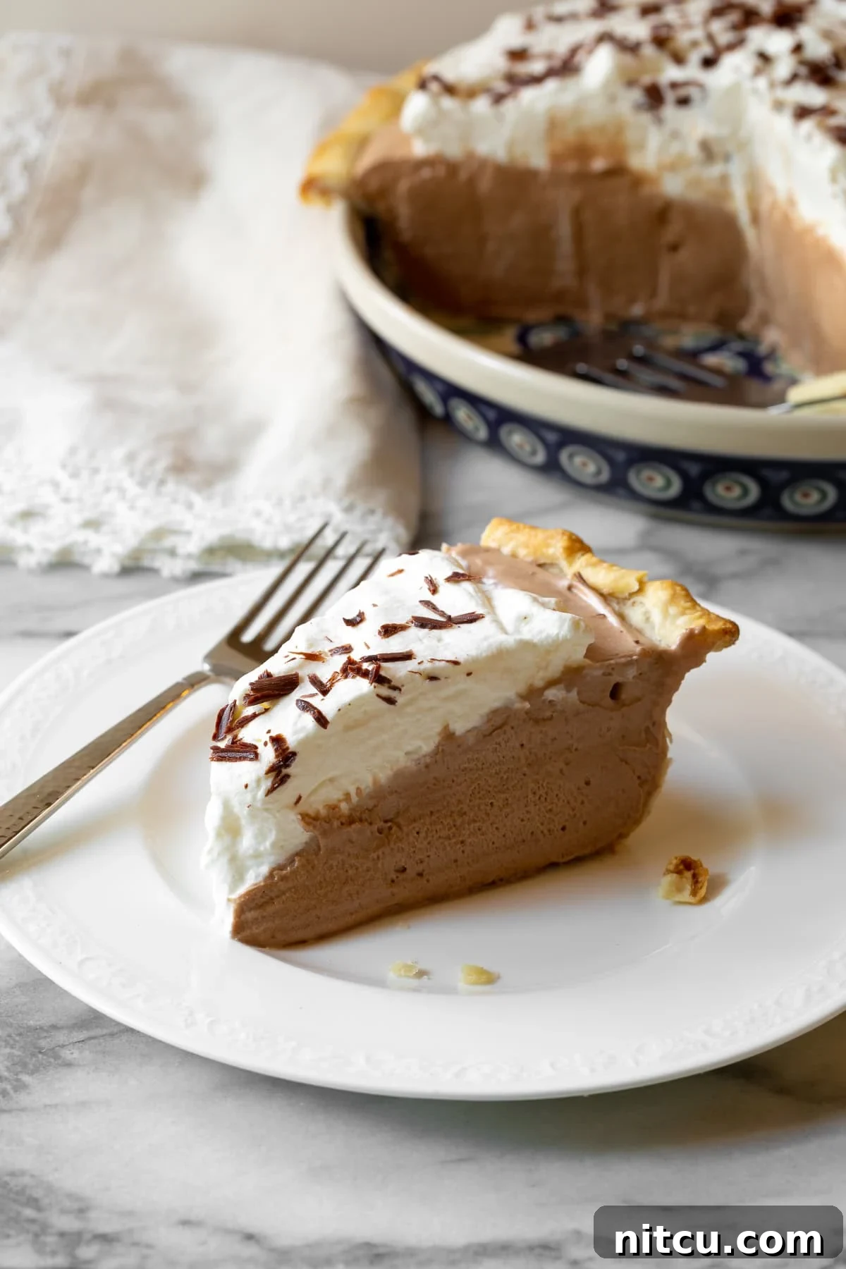 Velvety French Silk Pie 7 A slice of French Silk Pie on a plate, with a fork poised to take a bite, highlighting its creamy texture.