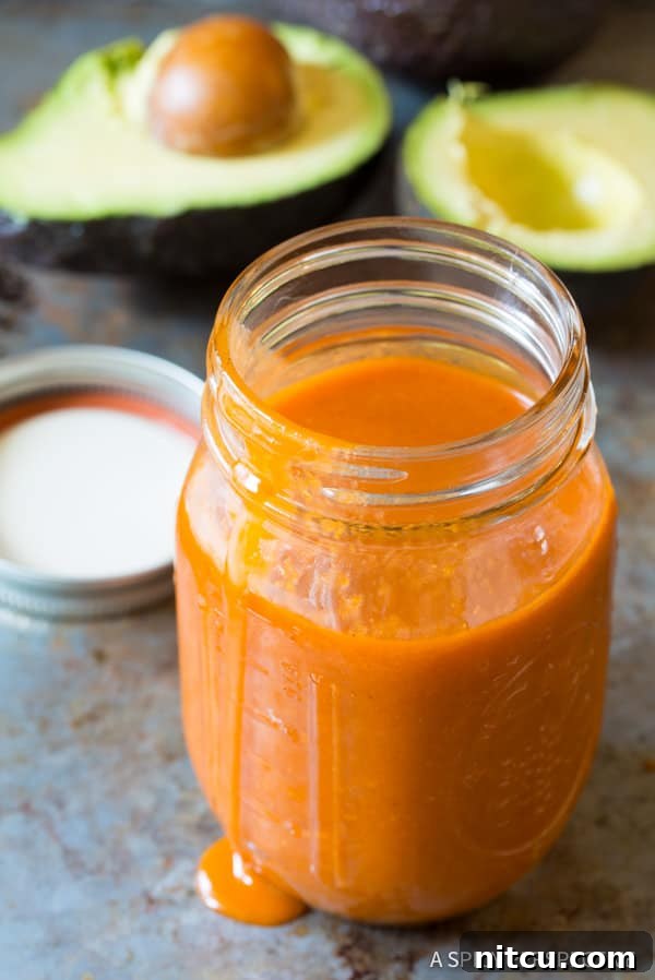 Legendary Dorito Taco Salad 5 Homemade Catalina Dressing in a clear glass mason jar, showcasing its vibrant color.