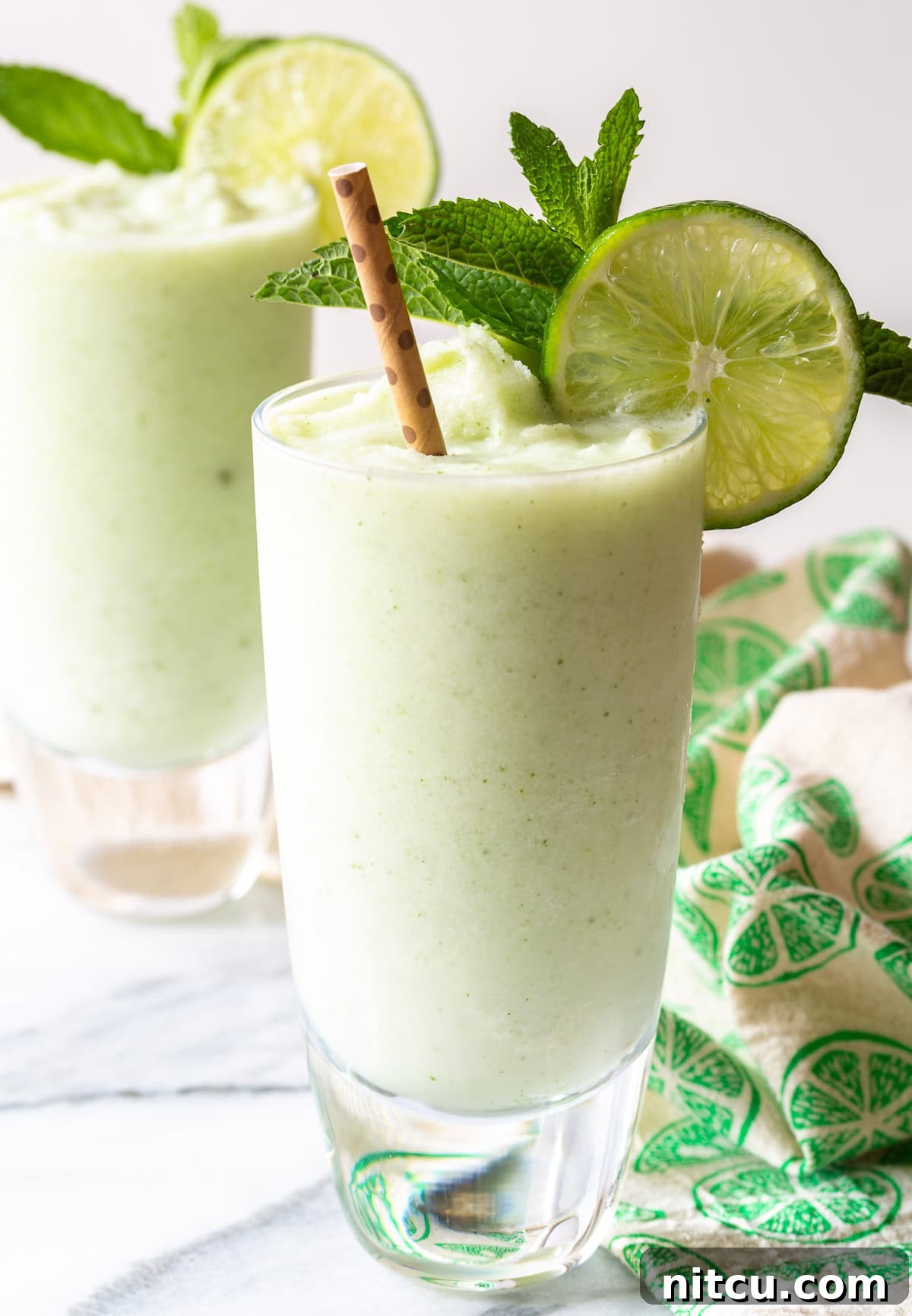 Frozen-Coconut-Mojito Creamy Frozen Coconut Mojito cocktail in a glass with mint and lime garnish