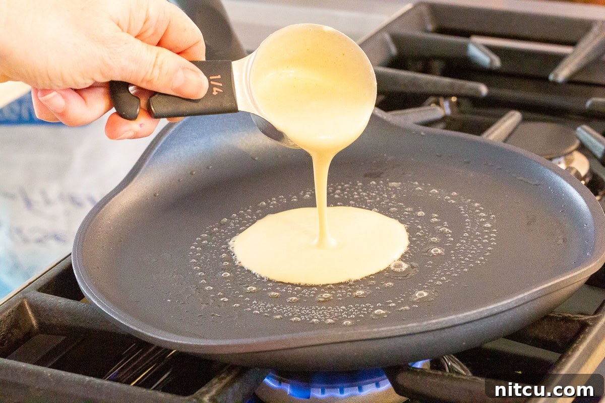 Golden Cheese Blintzes 5 Pouring thin blini batter onto a hot crepe pan to make delicate pancakes