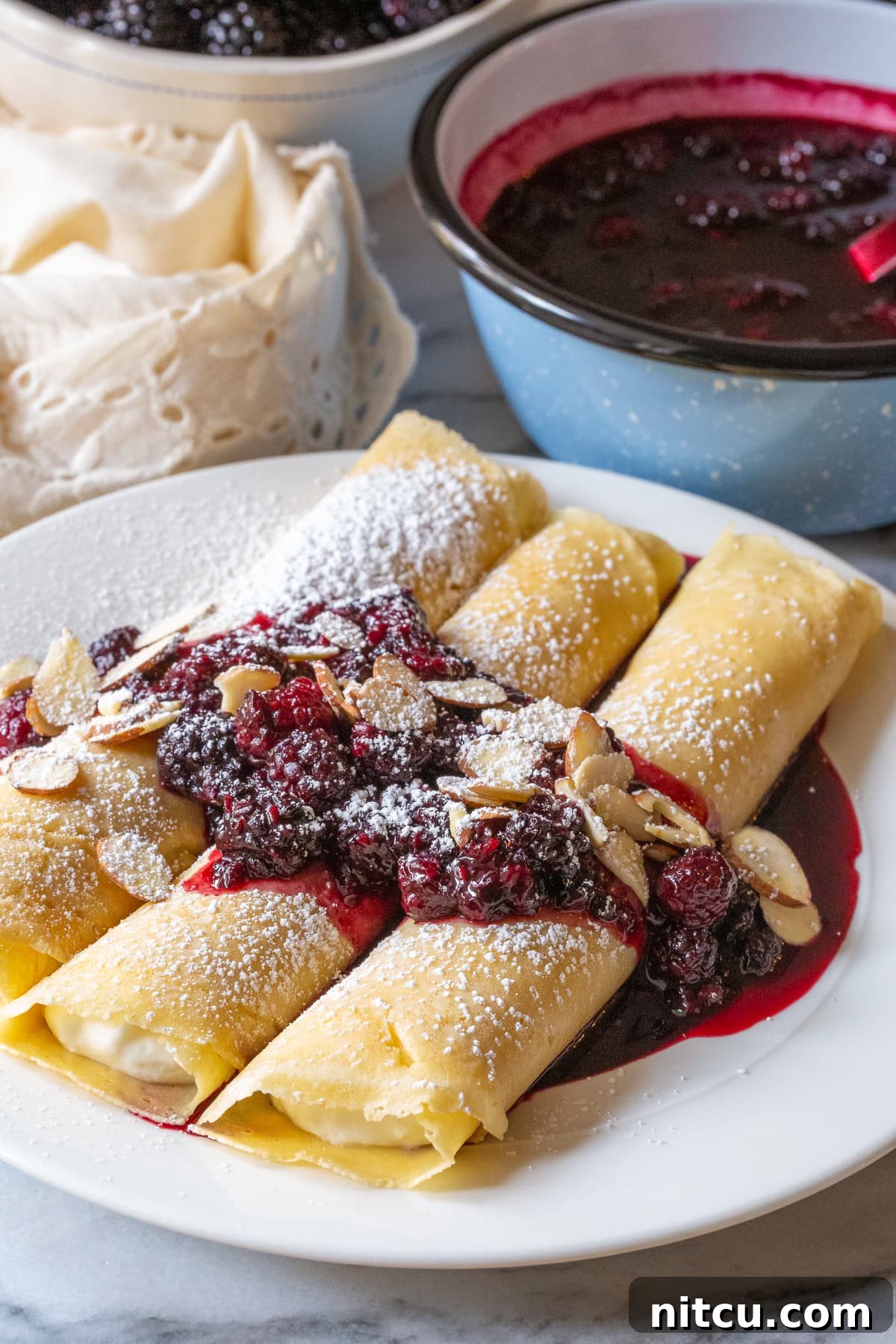 Golden Cheese Blintzes 9 Blintz pancakes served beautifully with blackberry sauce and sliced almonds, ready to enjoy