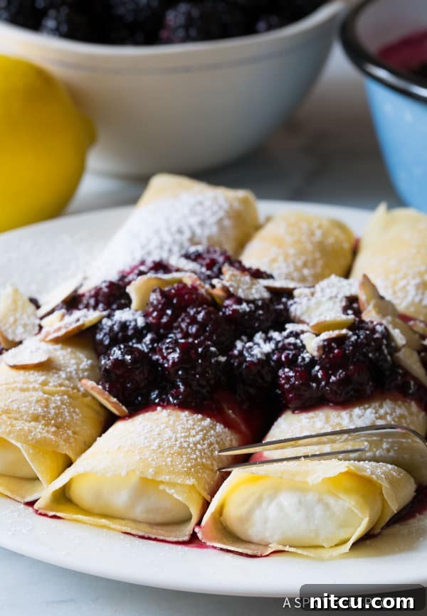 Golden Cheese Blintzes 10 Cream Filled Blintz Pancakes with berry sauce over the top, garnished with fresh berries