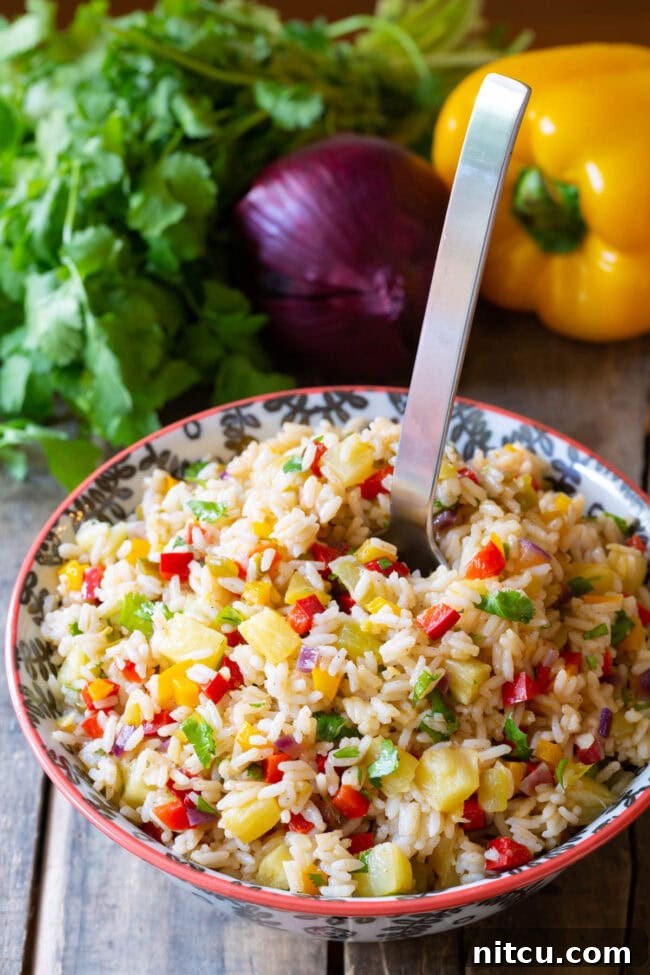Tropical Island Rice 7 Zesty Caribbean Confetti Rice Recipe in bowl with a large serving spoon.