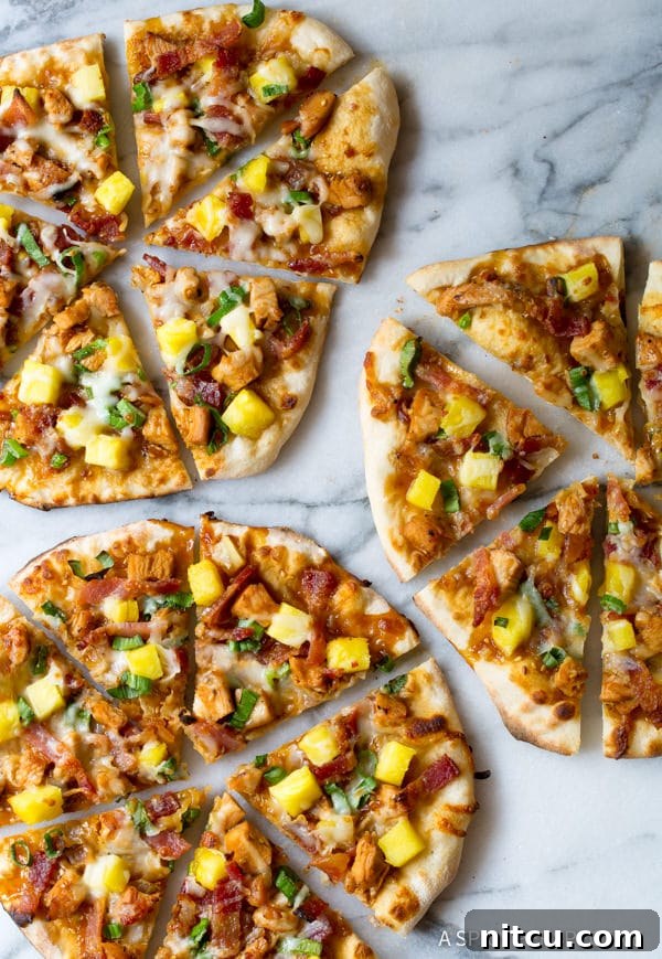 Umami Grilled Teriyaki Chicken Pizza 4 Overhead shot of Teriyaki Chicken Pizza slices with fresh pineapple and melted cheese on a white backdrop.