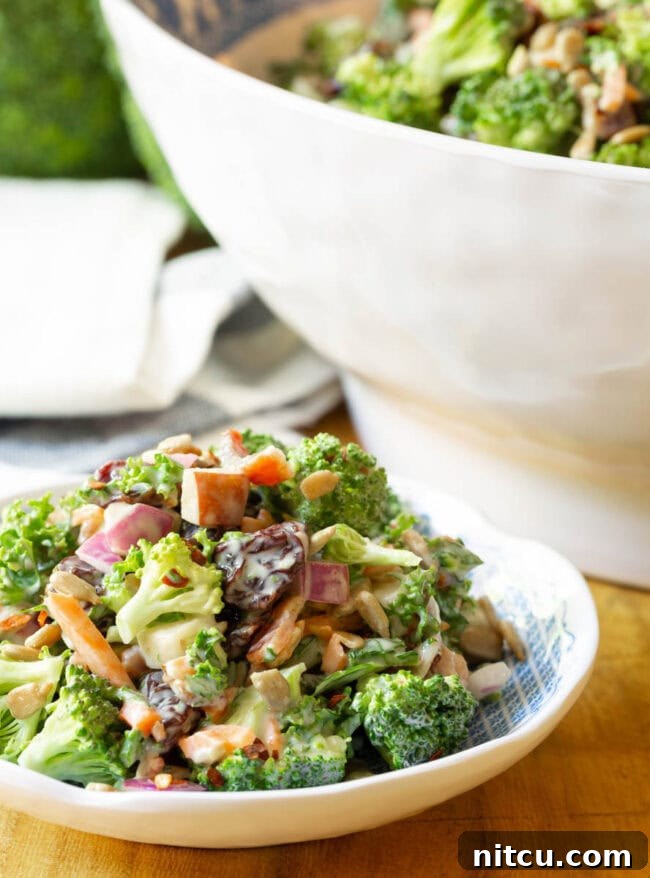 Broccoli Bacon Salad elegantly presented on a small white plate with the serving bowl in the soft background.