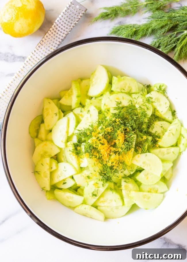 Crisp Cucumber Dill Delight 4 A candid shot of sliced cucumbers being gently tossed with creamy dill dressing in a mixing bowl, illustrating the preparation process.