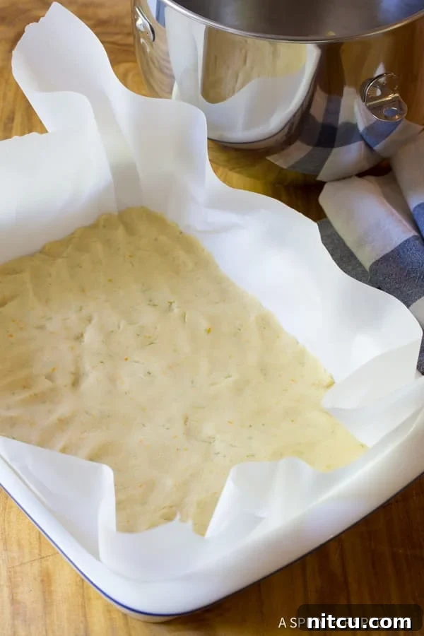 Fluffy cookie dough pressed into an even layer at the bottom of a baking dish, ready for the filling.