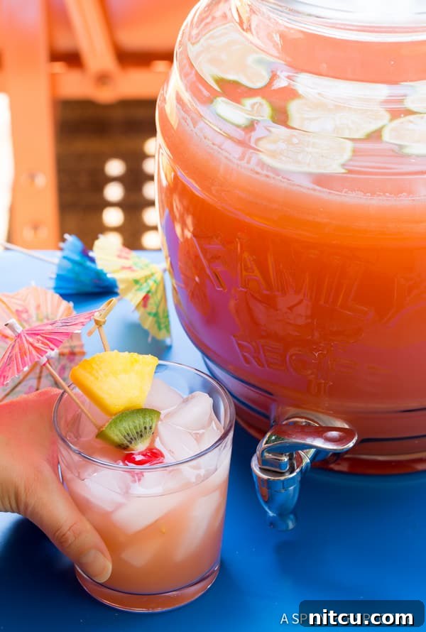 Single serving of Bahamian Blaster Rum Punch Hand holding a glass of Party Punch Recipe with Rum