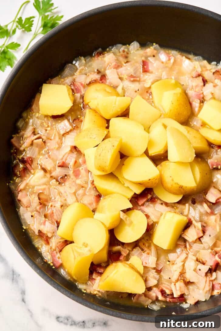 Tangy Warm German Potato Salad 7 Mixing potatoes with onion and bacon
