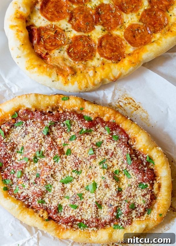 A top-down view of two slow cooker deep dish pizzas resting on a piece of white parchment paper, showcasing their thick crusts and abundant toppings.