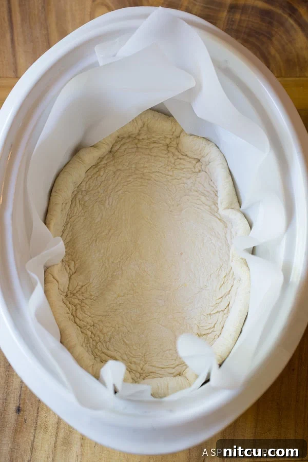 A top-down view of the raw pizza crust lining the crockpot, ready for toppings.