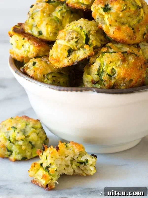 Crispy Zucchini Bites 7 A close-up of a half-eaten baked zucchini tot, revealing its tender, cheesy interior and crispy crust.