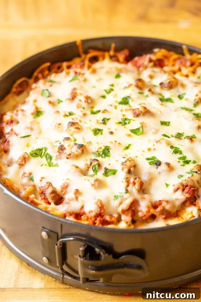 A slice of spaghetti pie on a plate with fresh salad and garlic bread.