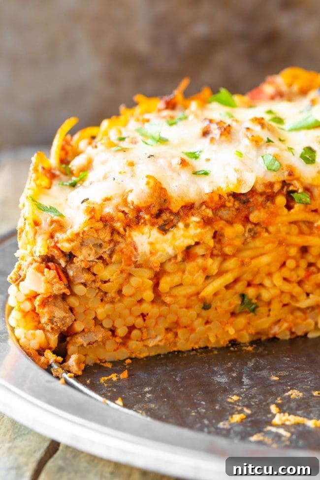 Baked spaghetti pie with a single piece cut out, showcasing its layers.
