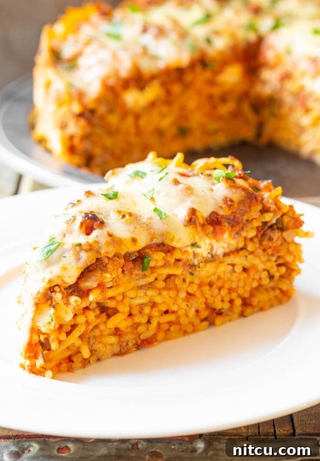 A single slice of baked spaghetti pie, showing the cheesy top and layered interior.