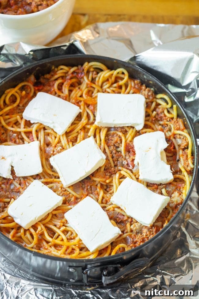Cooked spaghetti being mixed with meat sauce.