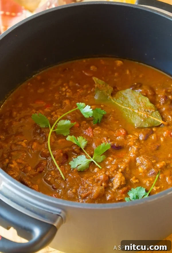 Pot of pumpkin chili recipe with cilantro and bay leaves. 