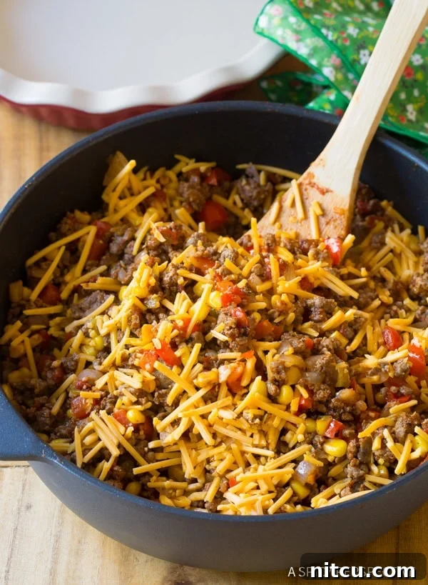 Shredded cheese being added to the ground beef filling. 