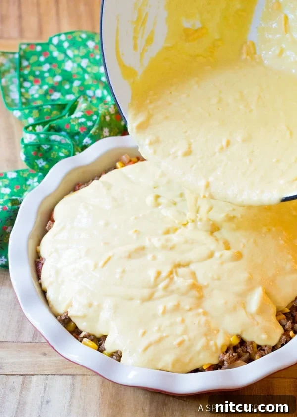 Corn masa topping being poured over cheesy beef filling. 