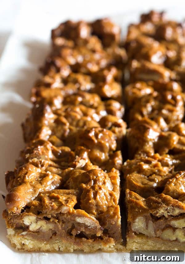 Caramel-Bars-Recipe Caramel pecan slab pie meticulously arranged on parchment paper, expertly cut into uniform bars.