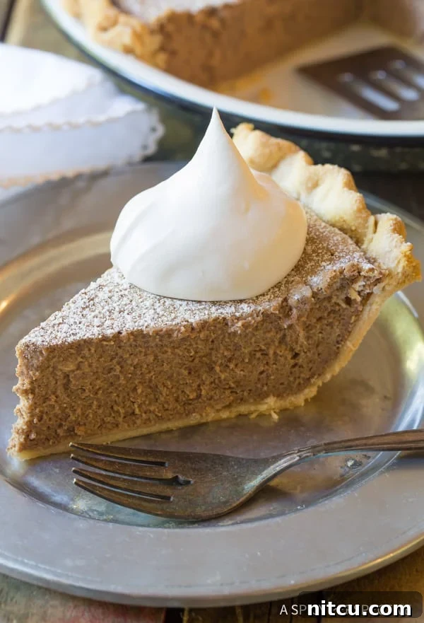 Slice of pie on a plate with a fork and whipped cream on top. 