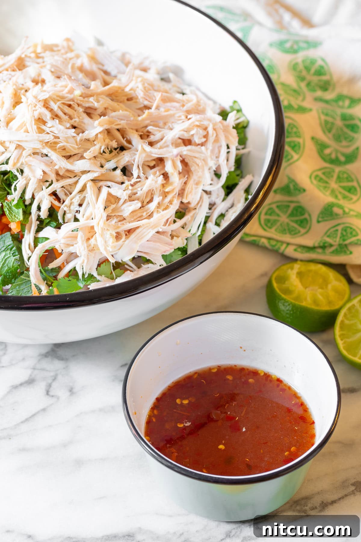 A vibrant cabbage salad in a large bowl, with a small white bowl of homemade nuoc cham dressing placed enticingly next to it, ready to be poured over.