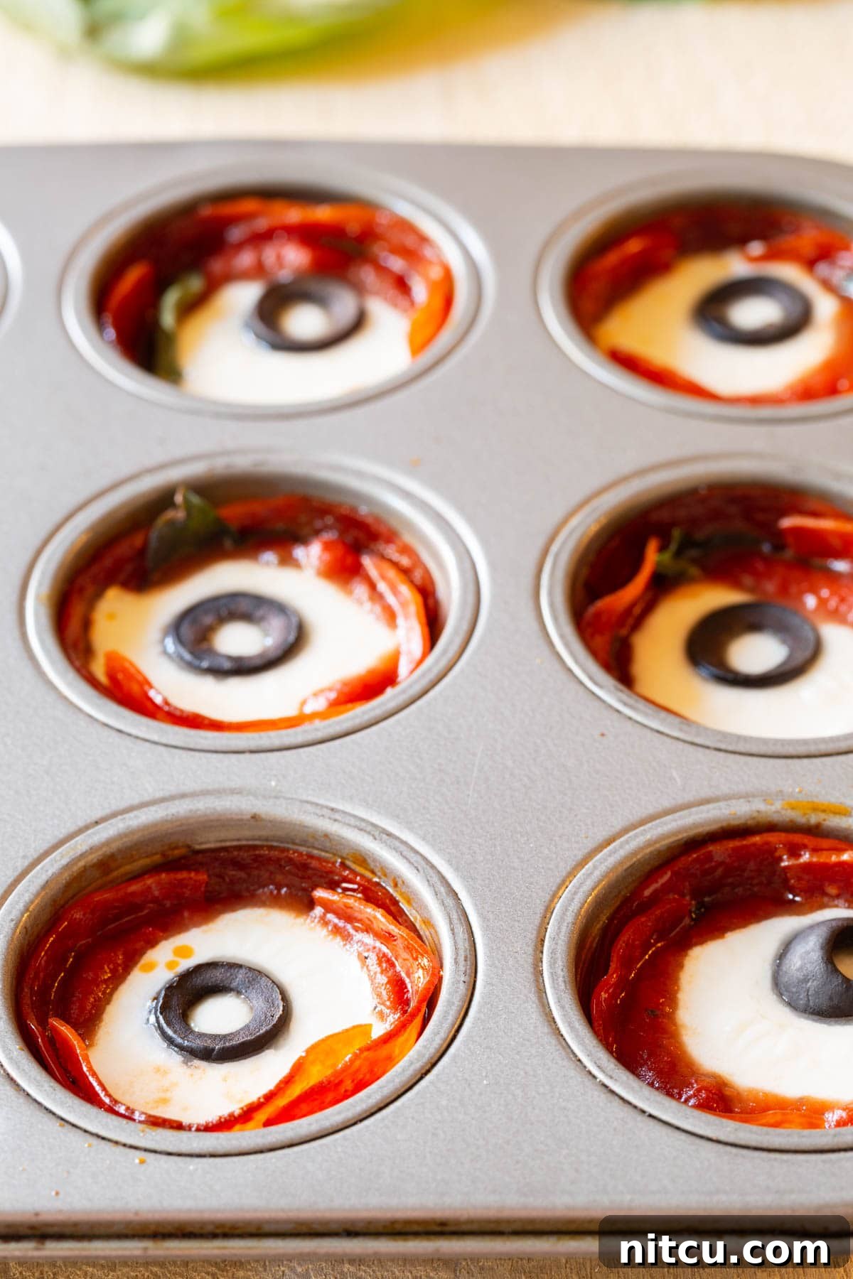 Savory Pepperoni Crisps 6 A vibrant close-up of baked pepperoni cups, their cheese perfectly melted and bubbly, garnished with fresh basil leaves, hot and ready to serve.