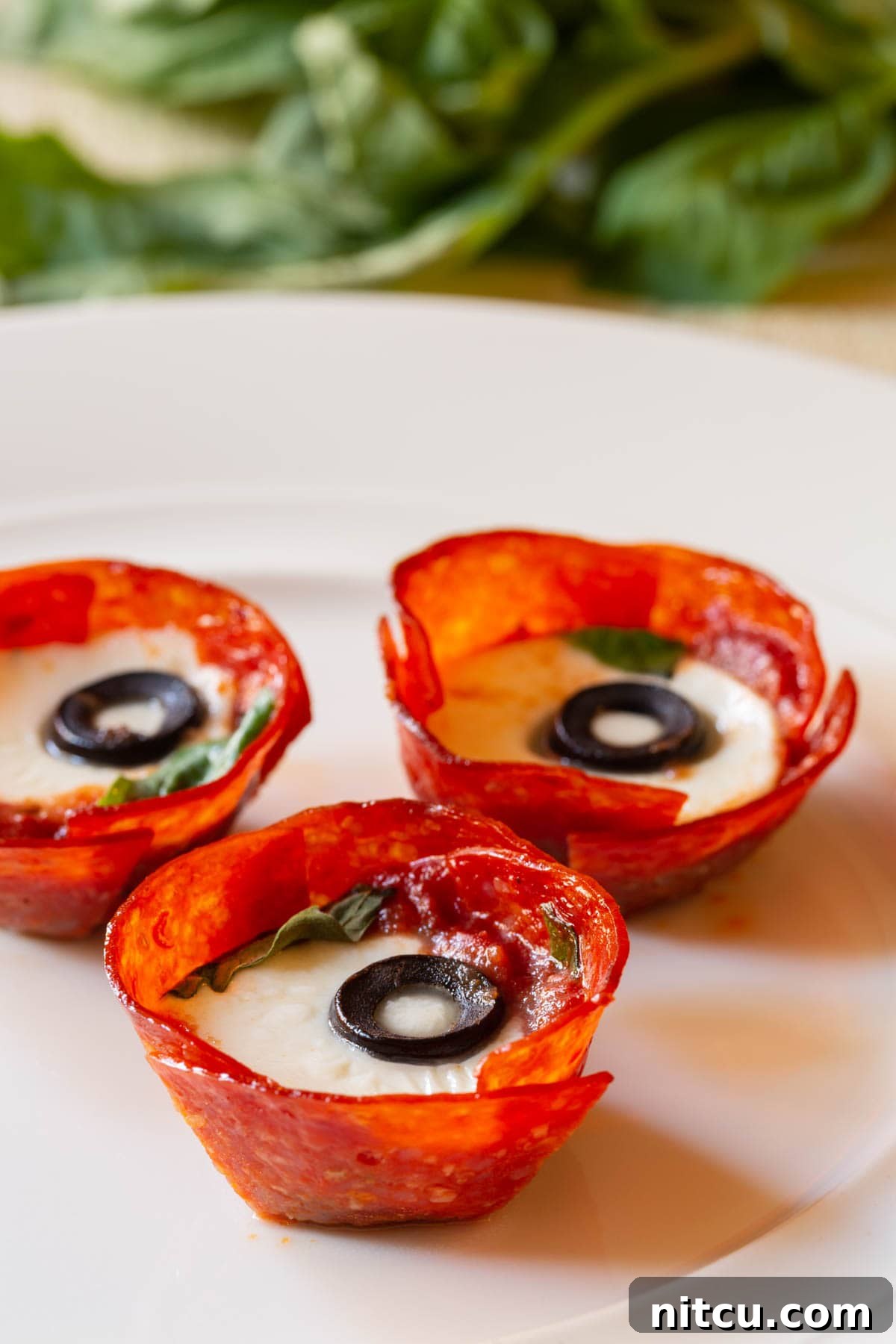 Savory Pepperoni Crisps 7 A mouth-watering close-up of a perfectly plated pepperoni cup, revealing its luscious melted cheese and crisp texture, garnished with fresh basil.