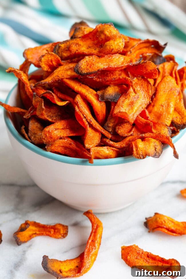 Crunchy Carrot Crisps 4 Perfectly baked carrot chips stacked in a vibrant bowl.