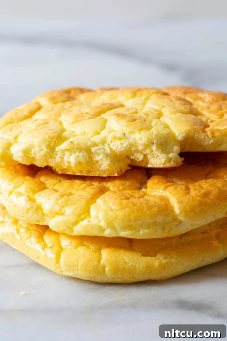 Cloud Bread Recipe #LowCarb #GlutenFree #GrainFree #Keto #CloudBread #KetoCloudBread #NoCarbBread Multiple pieces of cloud bread stacked, with one torn in half to reveal its soft, airy interior, showcasing its perfect texture.