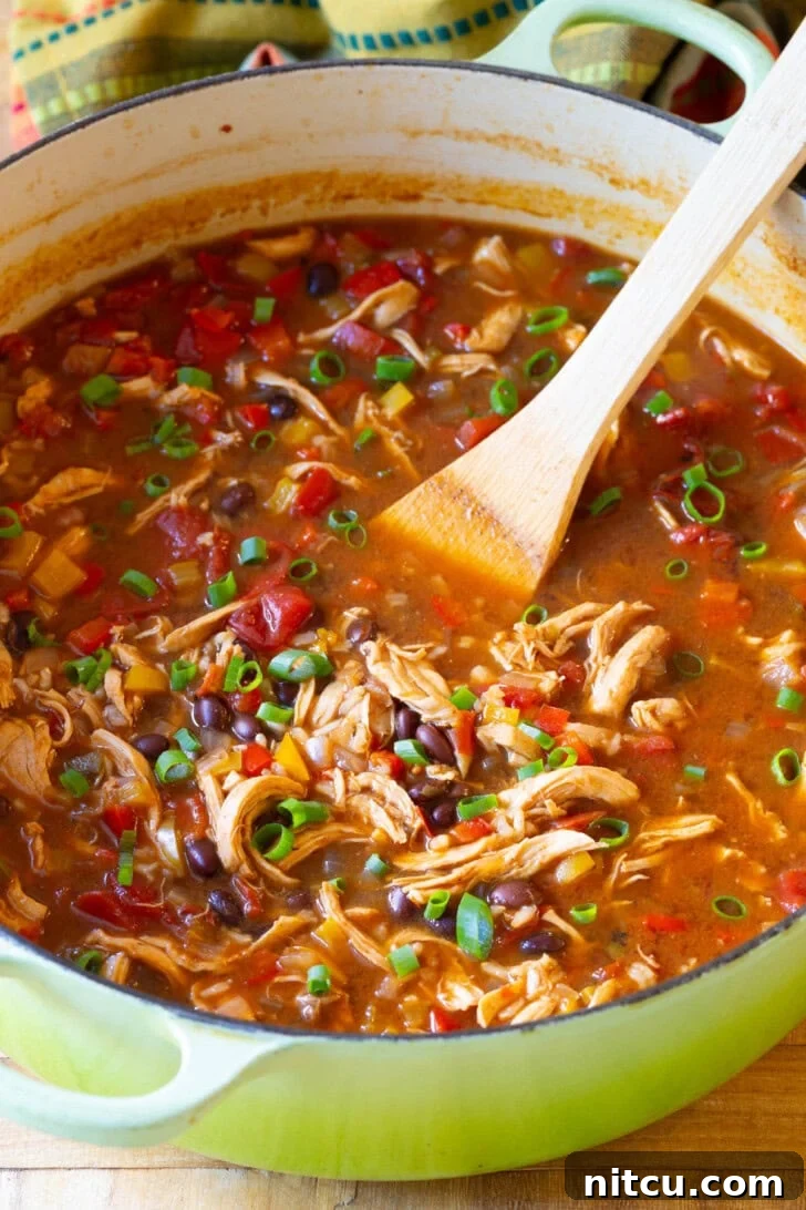 Chicken Fajita Soup in a Pot Chicken Fajita Soup simmering in a large green pot, showcasing chunks of chicken, black beans, bell peppers, and other vibrant vegetables.