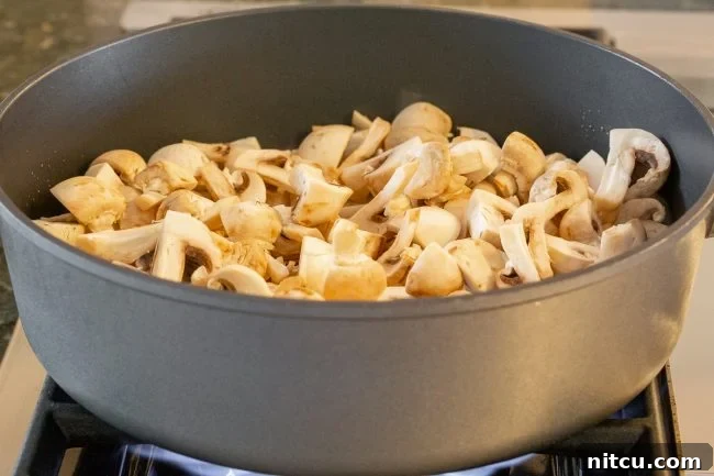 Button Mushrooms #ASpicyPerspective #Mushrooms #StirFry #MushroomStirFry #AsianMushroom #Asian #SideDish #Vegetarian #Healthy #LowCarb #LowFat Diced mushrooms being cooked in a skillet on the stove.