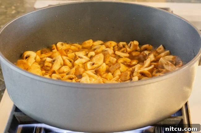 Savory Chinese Mushroom Stir-Fry 3 Mushrooms and sauce cooking in a skillet.