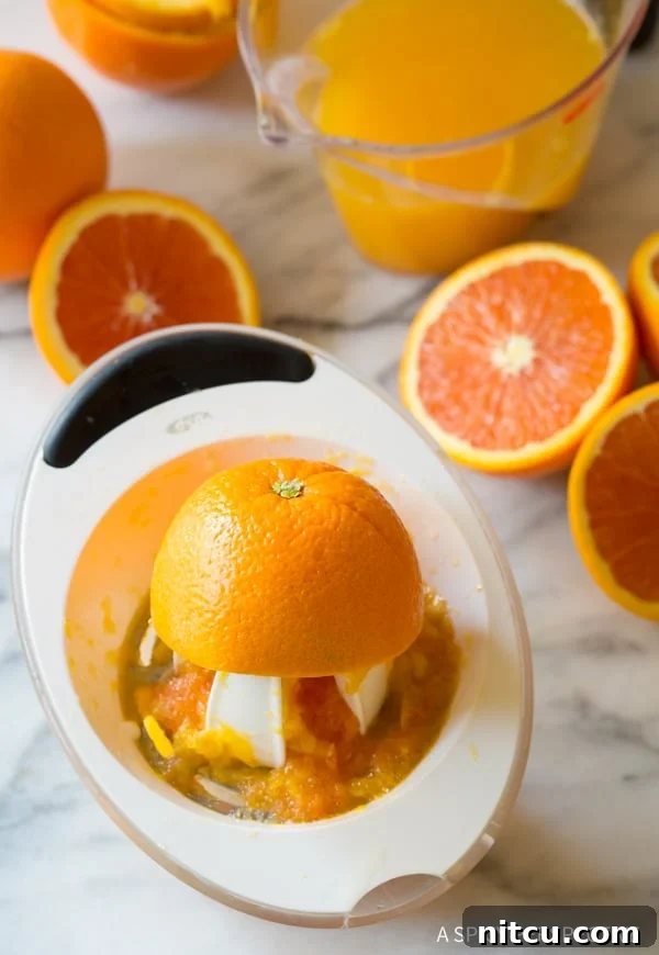 Juicing Fresh Oranges for Orangeade - Ingredient Prep Close-up view of fresh oranges being expertly juiced to extract their vibrant liquid, emphasizing the importance of fresh ingredients for a homemade Southern orangeade.