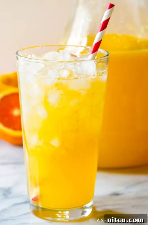 Glass of Refreshing Orangeade with Straw A close-up of a glass brimming with ice and homemade Southern orangeade, featuring a vibrant red and white striped straw, perfectly refreshing for summer.