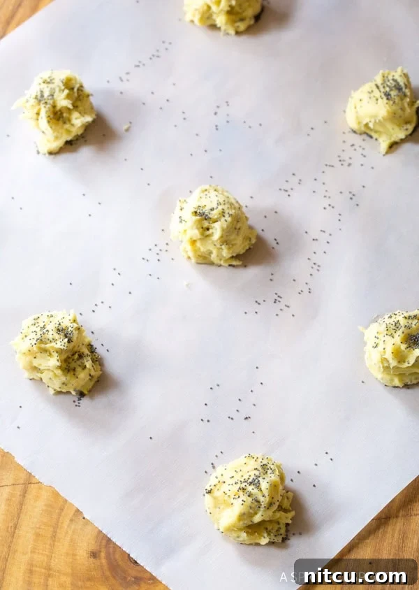 Lemon Poppy Seed Cookie Dough Ready to Bake Cookie dough balls neatly arranged on a baking sheet lined with parchment paper, ready for the oven.