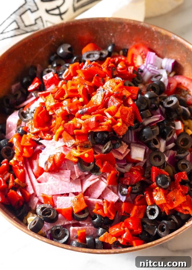 Salami slices and mini mozzarella balls, essential components for a flavorful Italian pasta salad.