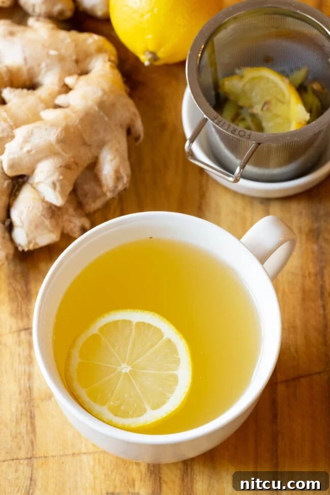 Sunshine Ginger Elixir 2 A close-up of a steaming cup of freshly made Lemon Ginger Detox Tea, showcasing the vibrant yellow lemon slices and grated ginger.