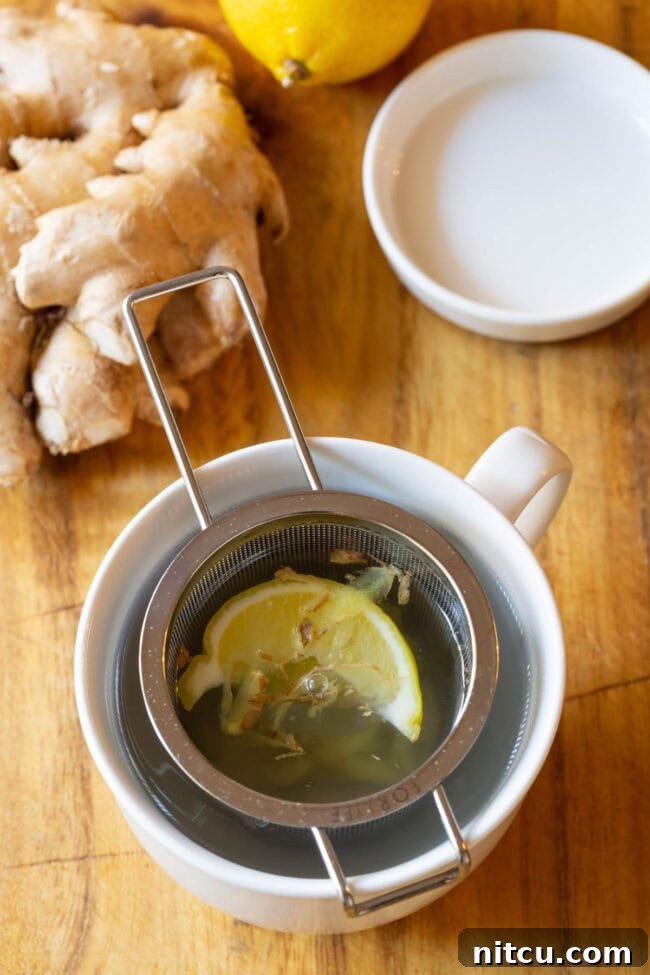 Sunshine Ginger Elixir 10 A comforting mug of Lemon Ginger Detox Tea with a tea infuser, ready to be enjoyed.