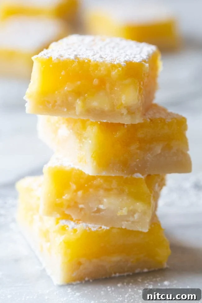 Lemon Bars #ASpicyPerspective #Lemon #Bars #LemonBars #LemonSquares #CookieCrust #WhiteChocolate #Spring #Dessert #Easter White Chocolate Lemon Bars Recipes - the best bars stacked on plate