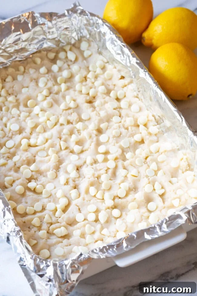 Cookie Crust #ASpicyPerspective #Lemon #Bars #LemonBars #LemonSquares #CookieCrust #WhiteChocolate #Spring #Dessert #Easter Layer recipe for lemon bars - Cookie Crust and white chocolate chips