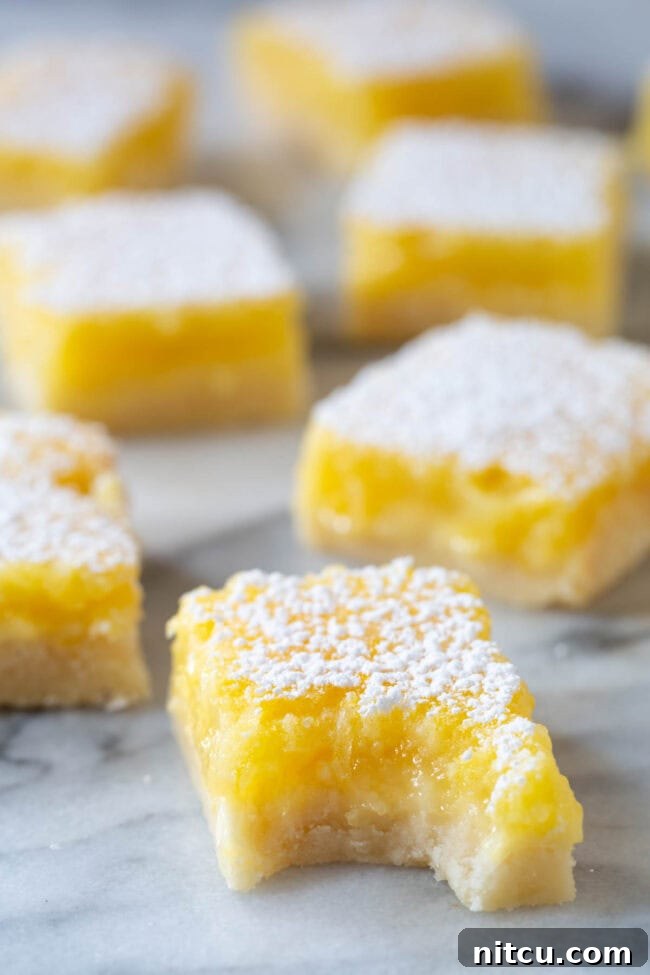 Lemon Bar Recipe #ASpicyPerspective #Lemon #Bars #LemonBars #LemonSquares #CookieCrust #WhiteChocolate #Spring #Dessert #Easter Best Lemon Bar Recipe - bite taken out