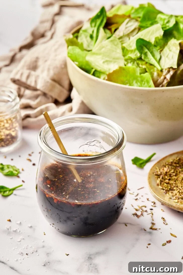 Elevate Your Salad with Homemade Balsamic Vinaigrette 10 Balsamic vinaigrette in a jar with a salad in the background.
